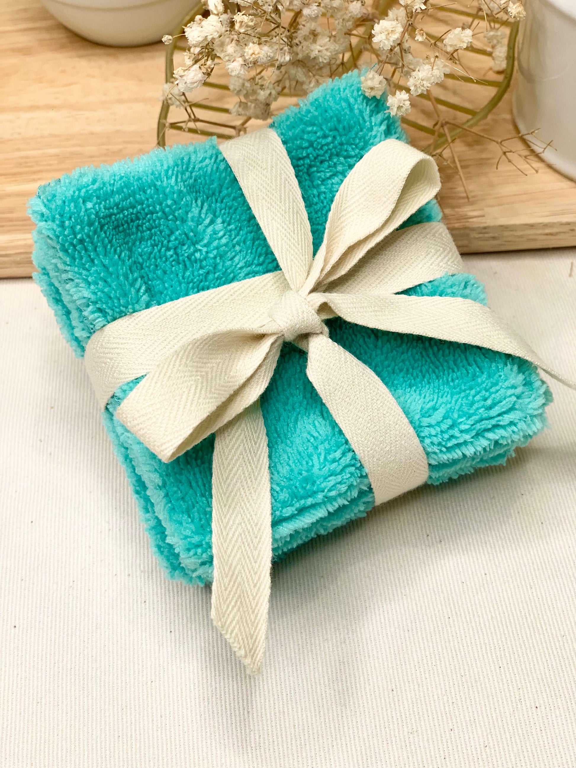 Gros plan sur la texture ultra douce de l'éponge de bambou et le tissu coton certifié Oeko-Tex d'un carré démaquillant artisanal